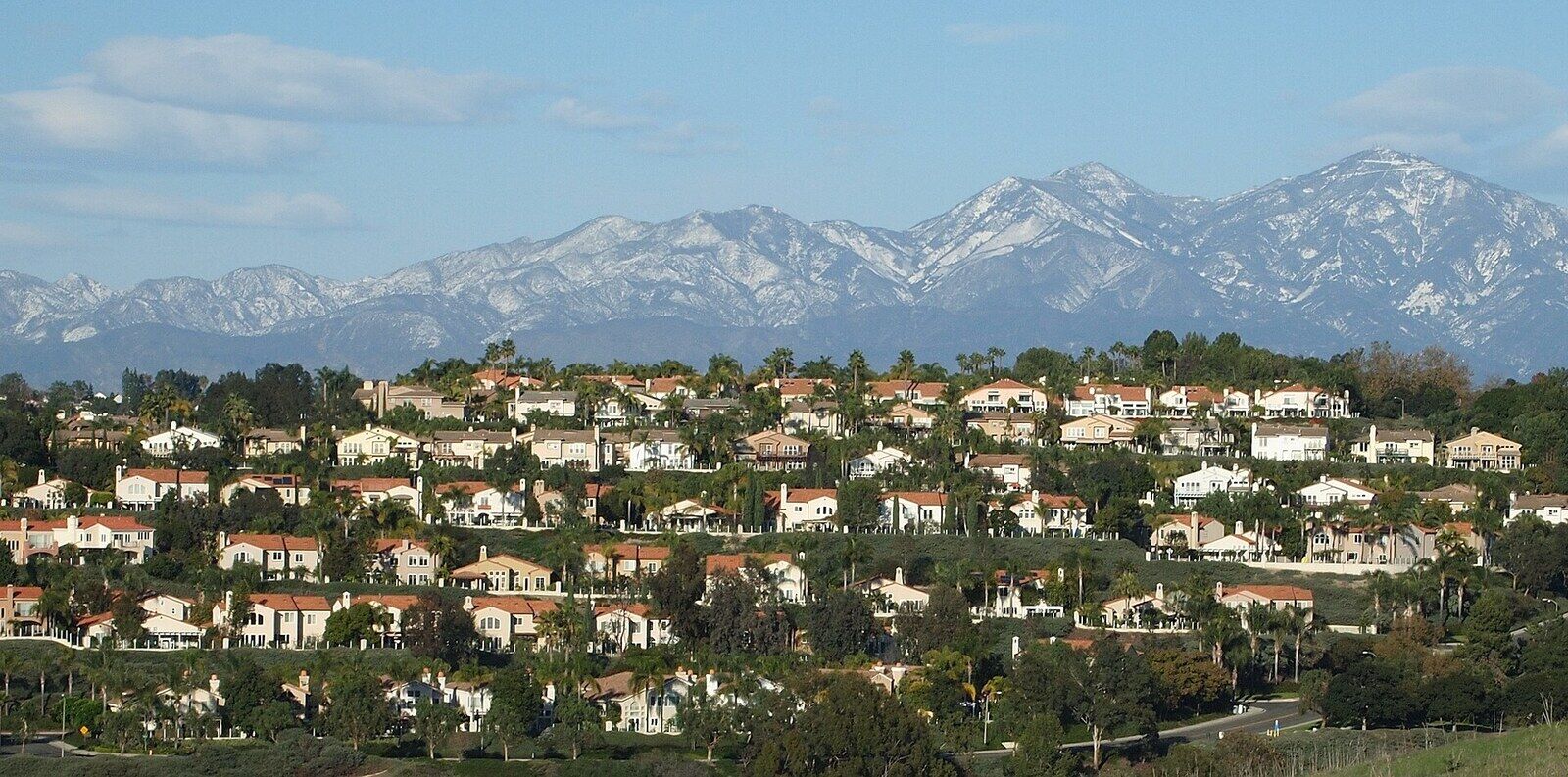 Rows of tile-roofed homes on a hillside in Laguna Niguel with mountains behind
